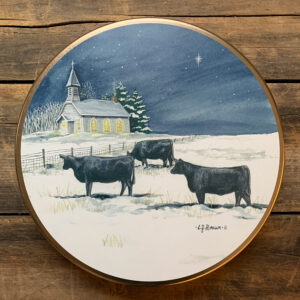 Tin with design of 3 black cows in a snowy field with a church in the background