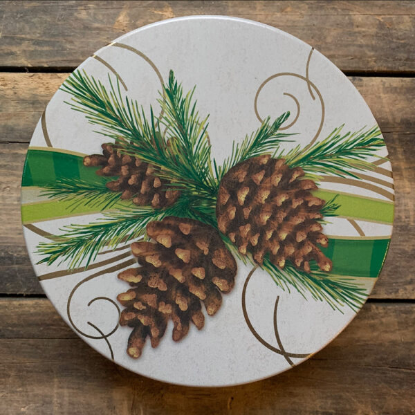 white tin with image of pinecones, branches and green ribbon